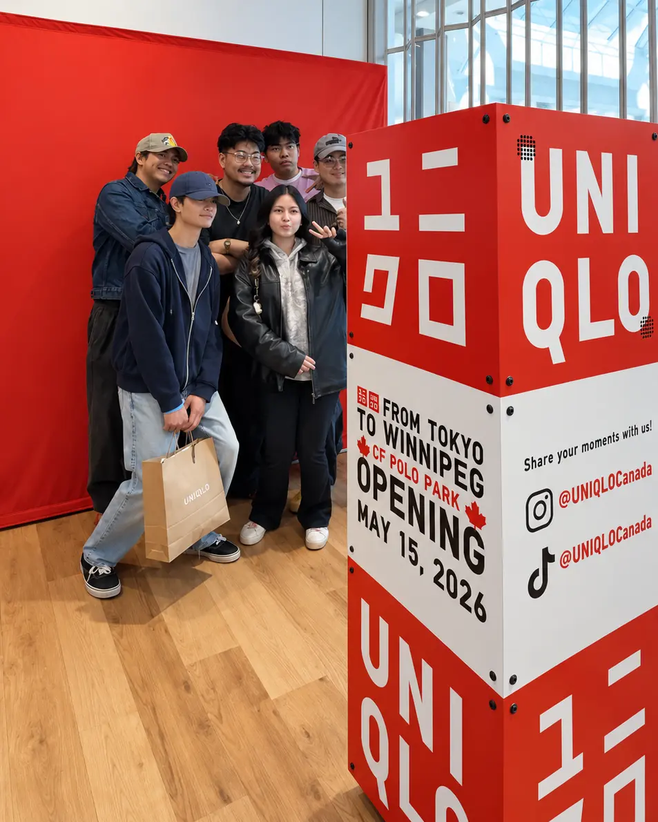 Six guests pose beside the custom red-and-white UNIQLO photo booth at CF Polo Park