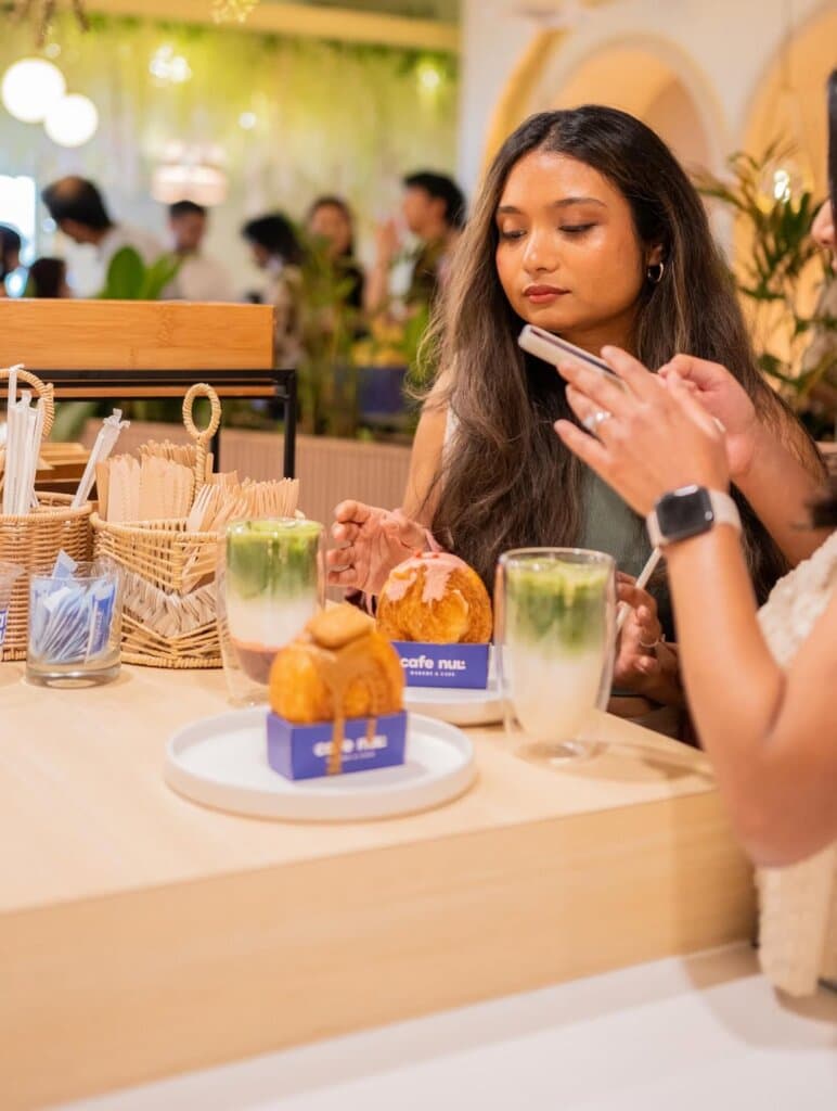 A café visitor at the CAFE NUL counter with drinks and pastries